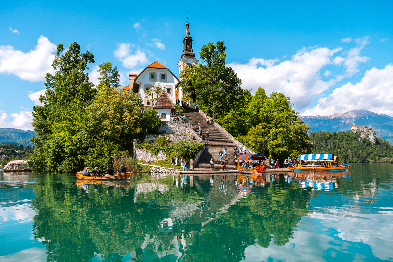 Tourists arrive at Bled Island aboard traditional pletna boats, ready to explore the famous Church of the Assumption. A must-visit highlight of Lake Bled and a symbol of Slovenia’s natural and cultural beauty.