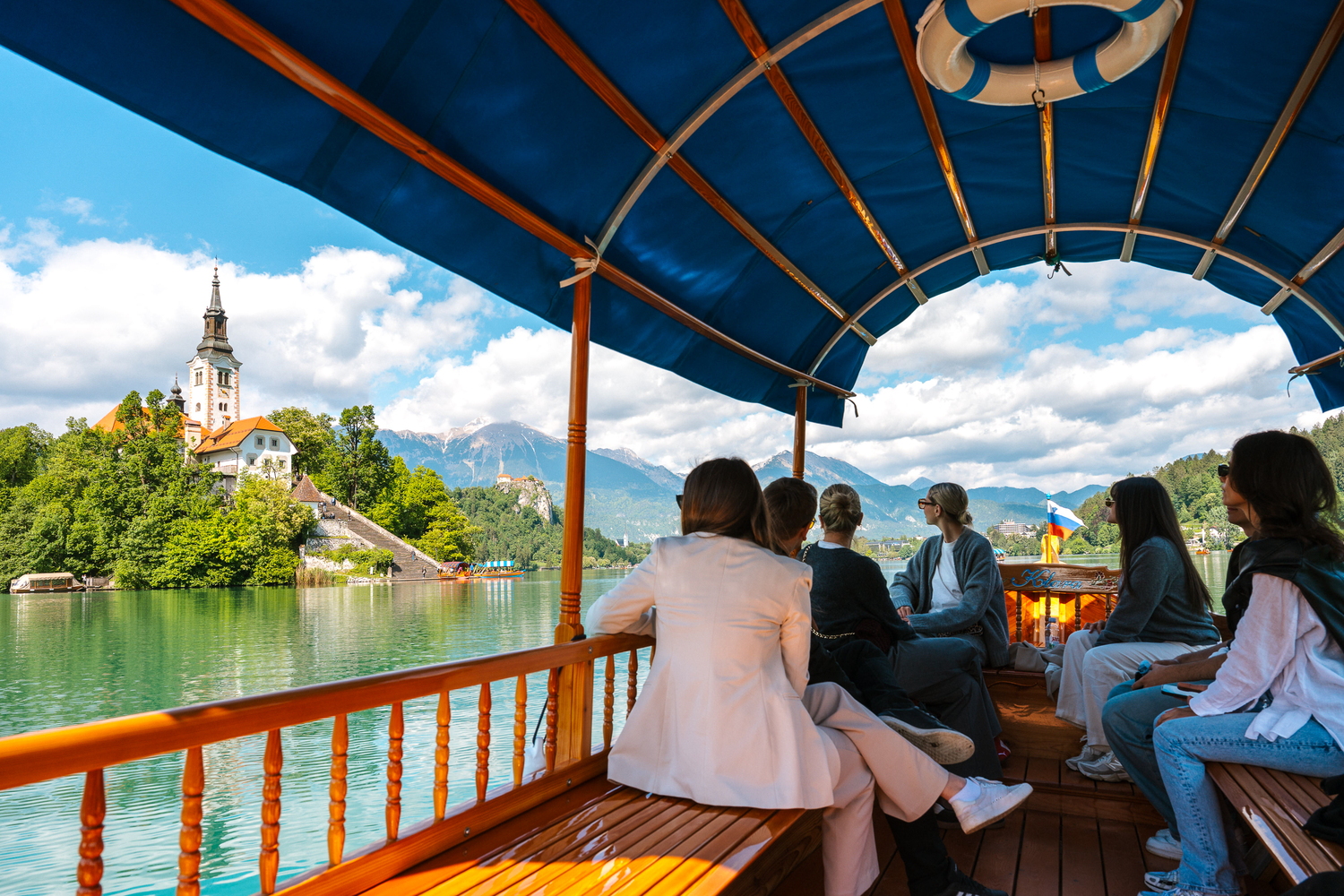 Tourists enjoy a peaceful ride on traditional pletna boats across the crystal-clear waters of Lake Bled, one of Slovenia’s top travel destinations.