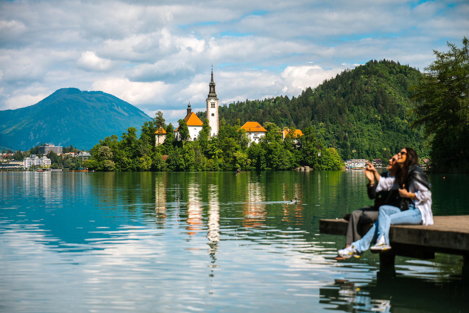 Two happy tourists enjoy the stunning views and relaxed atmosphere of Lake Bled, one of Slovenia’s most popular travel spots.