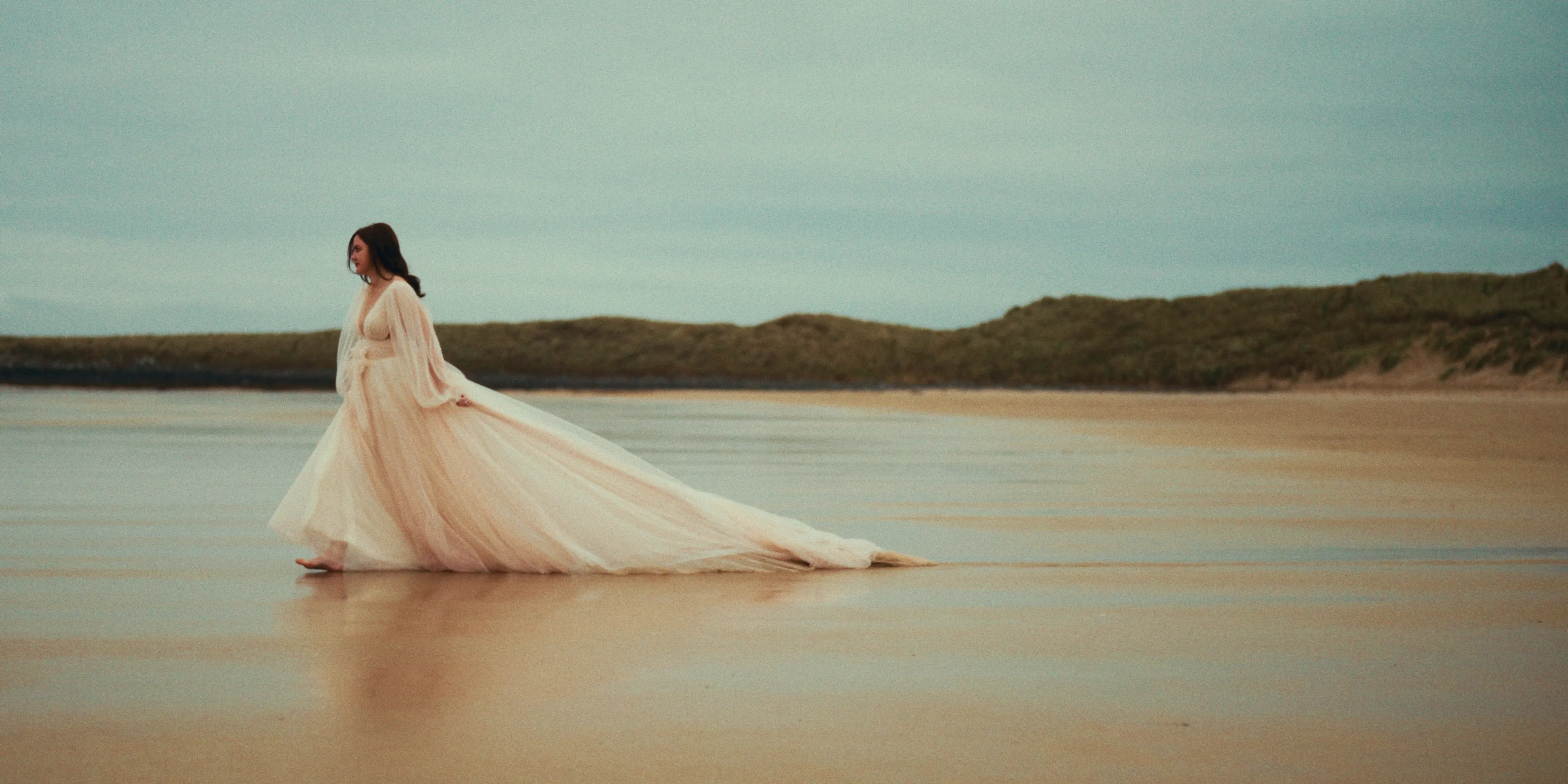Bride walking on the beach in her wedding dress at Newton Hall