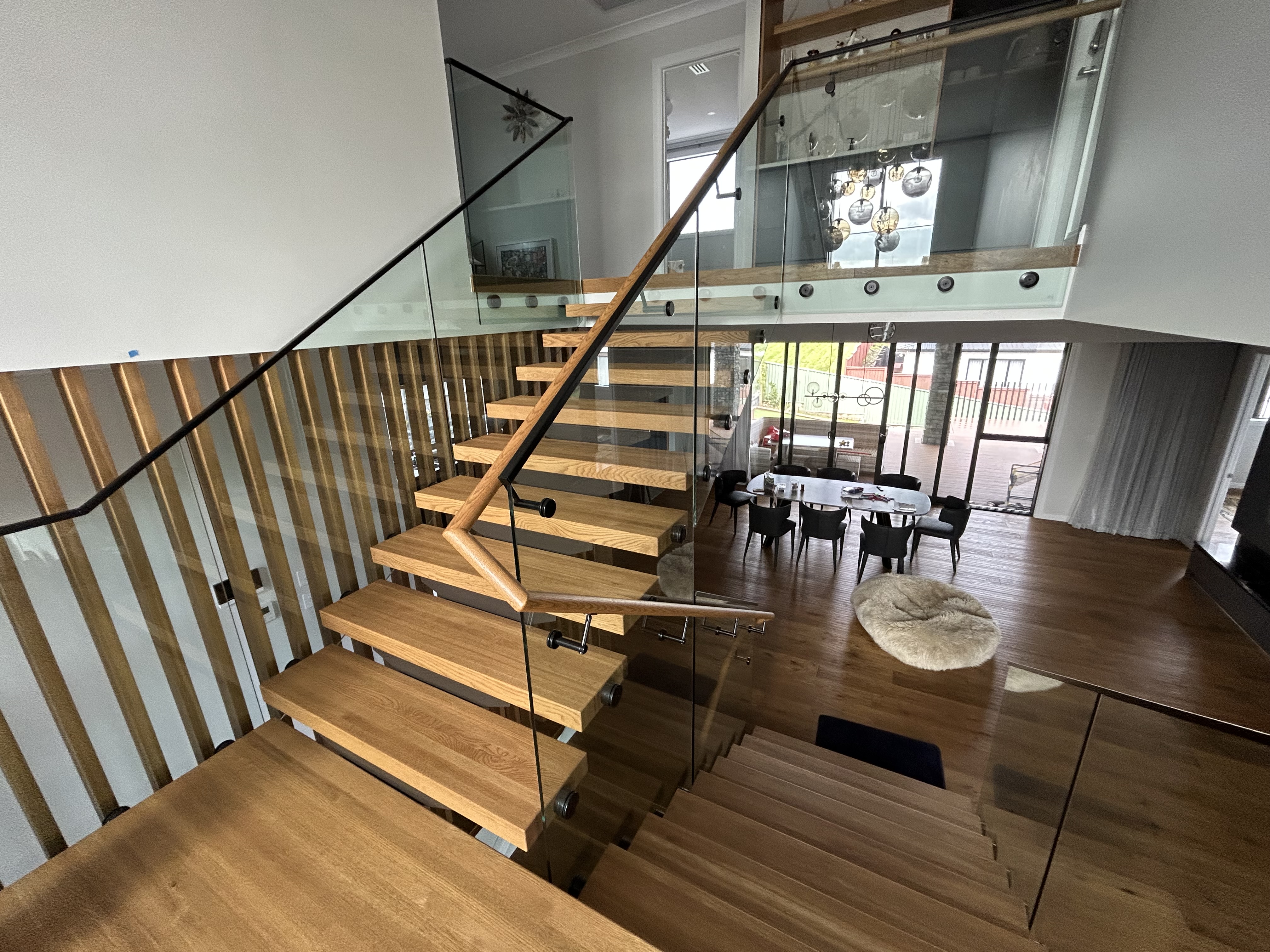 switchback timber floating stairs with glass balustrades in a minimalist home