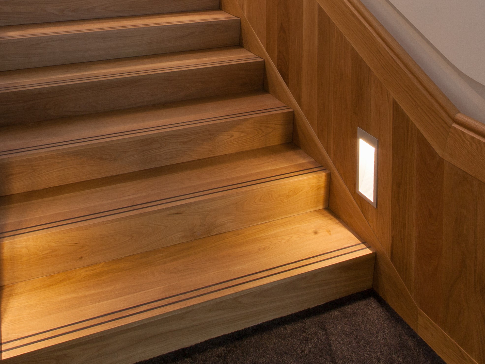 closeup of timber stairs with wood panel balustrade and stair lighting