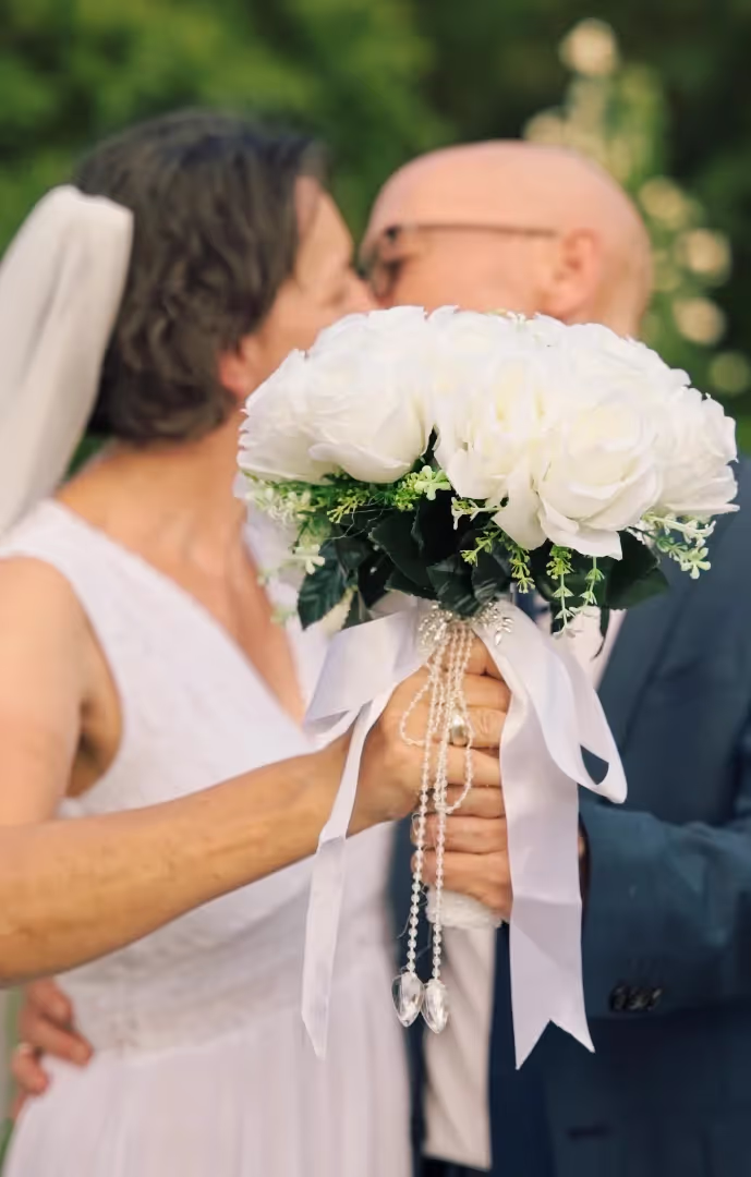 Bride and groom kissing behind flowers