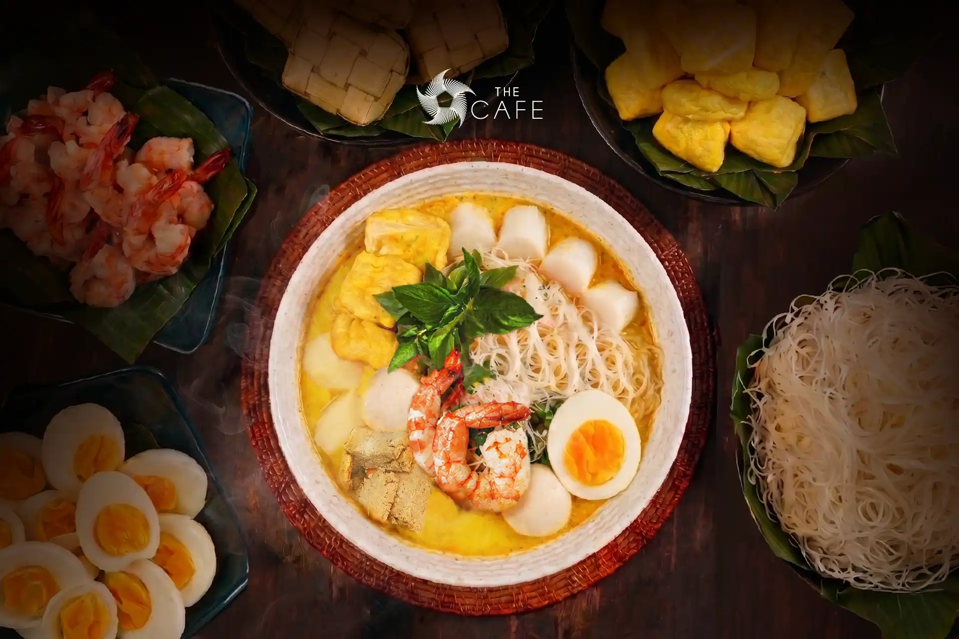 A bowl of Laksa Khas Bogor served with coconut broth, rice cakes, vermicelli, prawns, egg, and traditional accompaniments at The Cafe, Hotel Mulia Senayan.