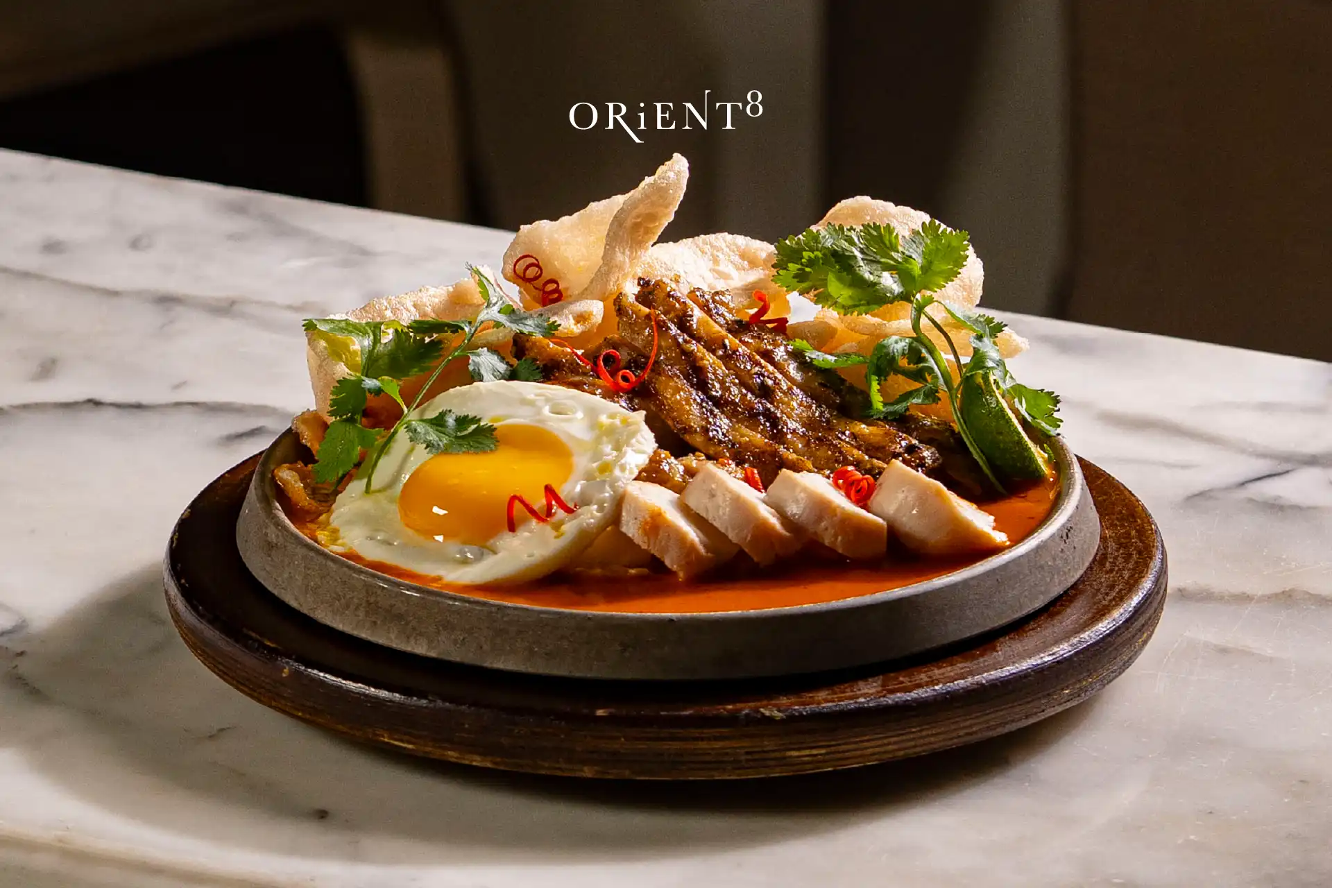 Asian rice dish with grilled meat, fried egg, and crispy crackers at Orient8, part of Hotel Mulia's Rice Around Asia dining promotion.