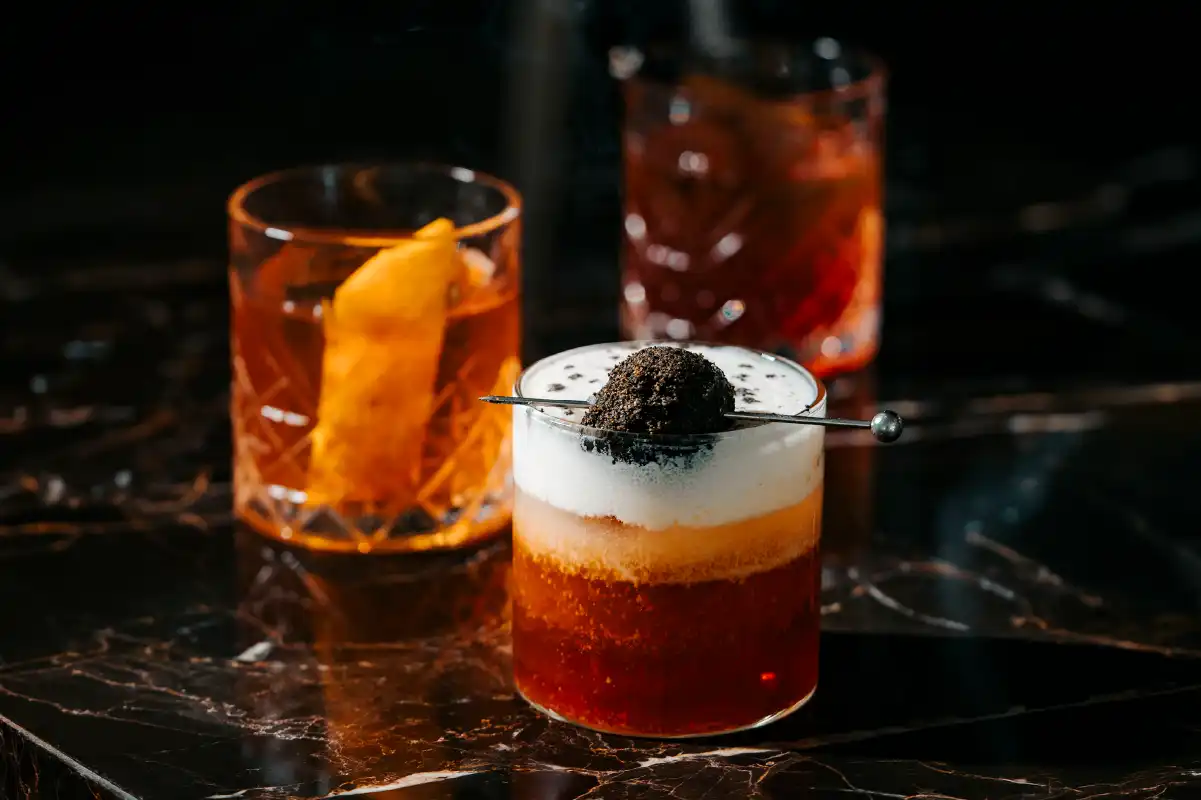 Layered Negroni cocktail with foam and charcoal garnish, promoting Negroni Cocktail Week at CJ's Bar, bleu8 and il Mare, Hotel Mulia Senayan,Jakarta.