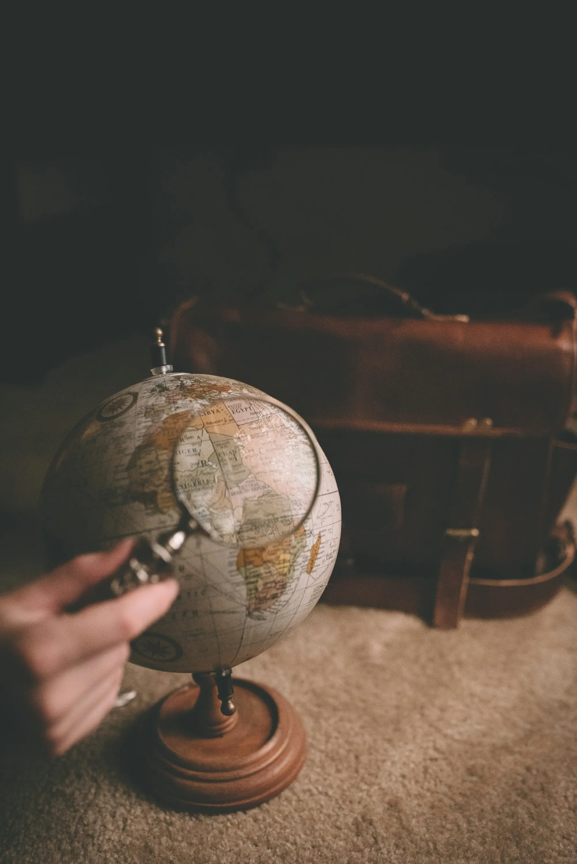 Hand holding a magnifying glass over a globe symbolizing global talent search