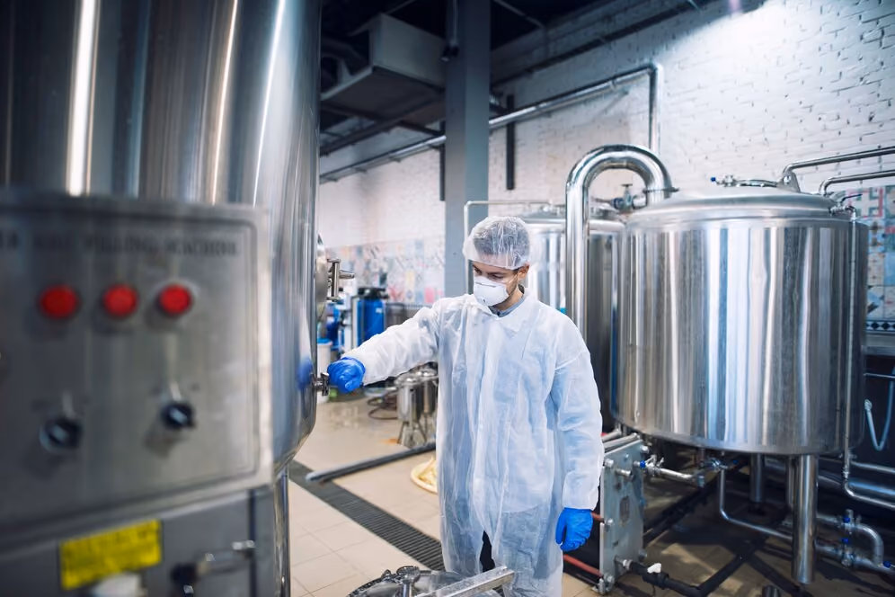 Worker operating industrial equipment and adjusting a large storage tank