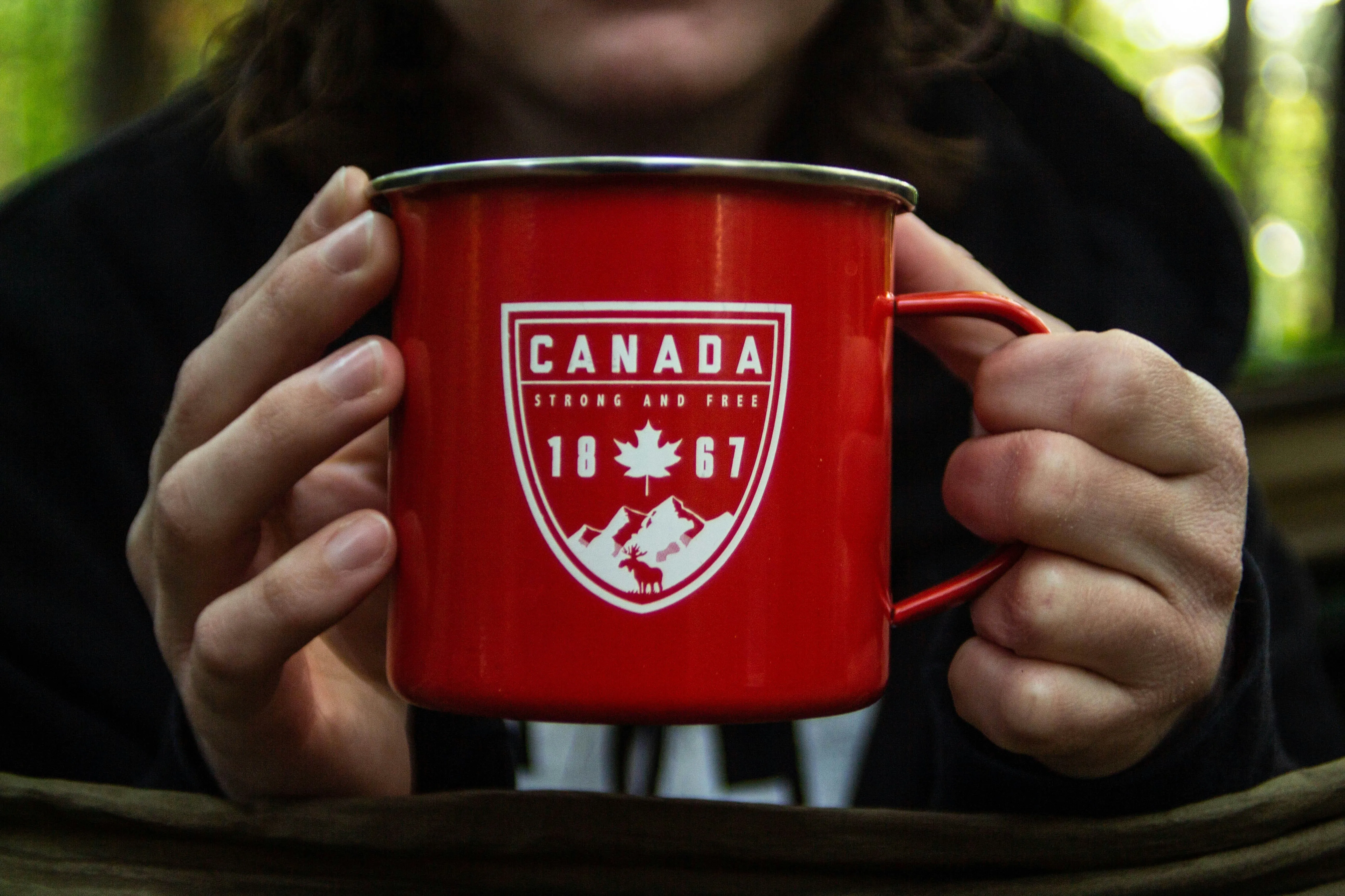 Man holding a coffee mug featuring a Canadian flag design