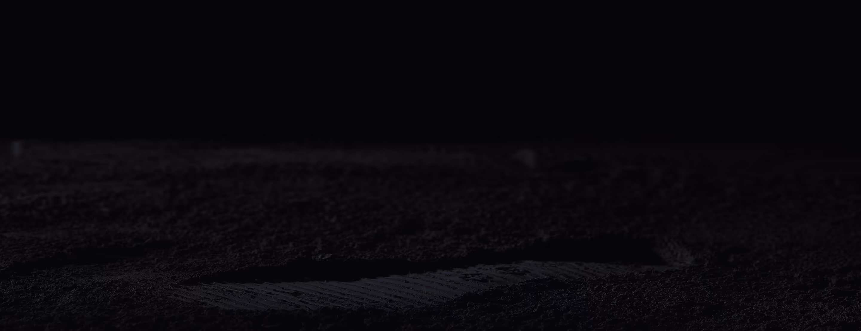 Tire track imprint on dark, damp soil under low light.