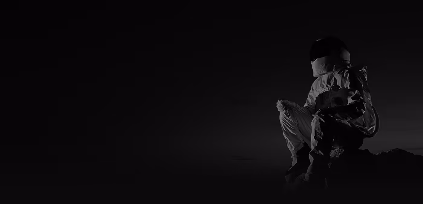 Astronaut sitting on a rock against a dark background, looking contemplative.
