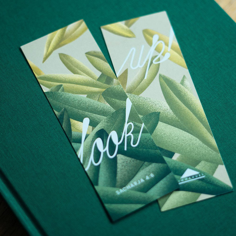 Zwei Lesezeichen mit grün-gelben Blättermustern und den Worten „look!“ und „ups!“ liegen auf einem grünen Buch.