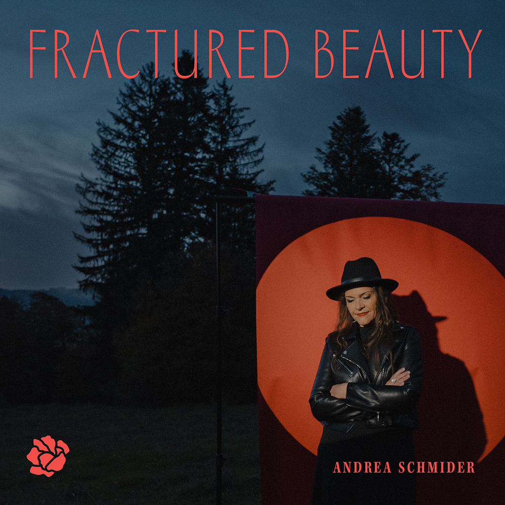 Frau in Lederjacke und Hut steht vor rotem Kreis bei Dämmerung mit Bäumen im Hintergrund.