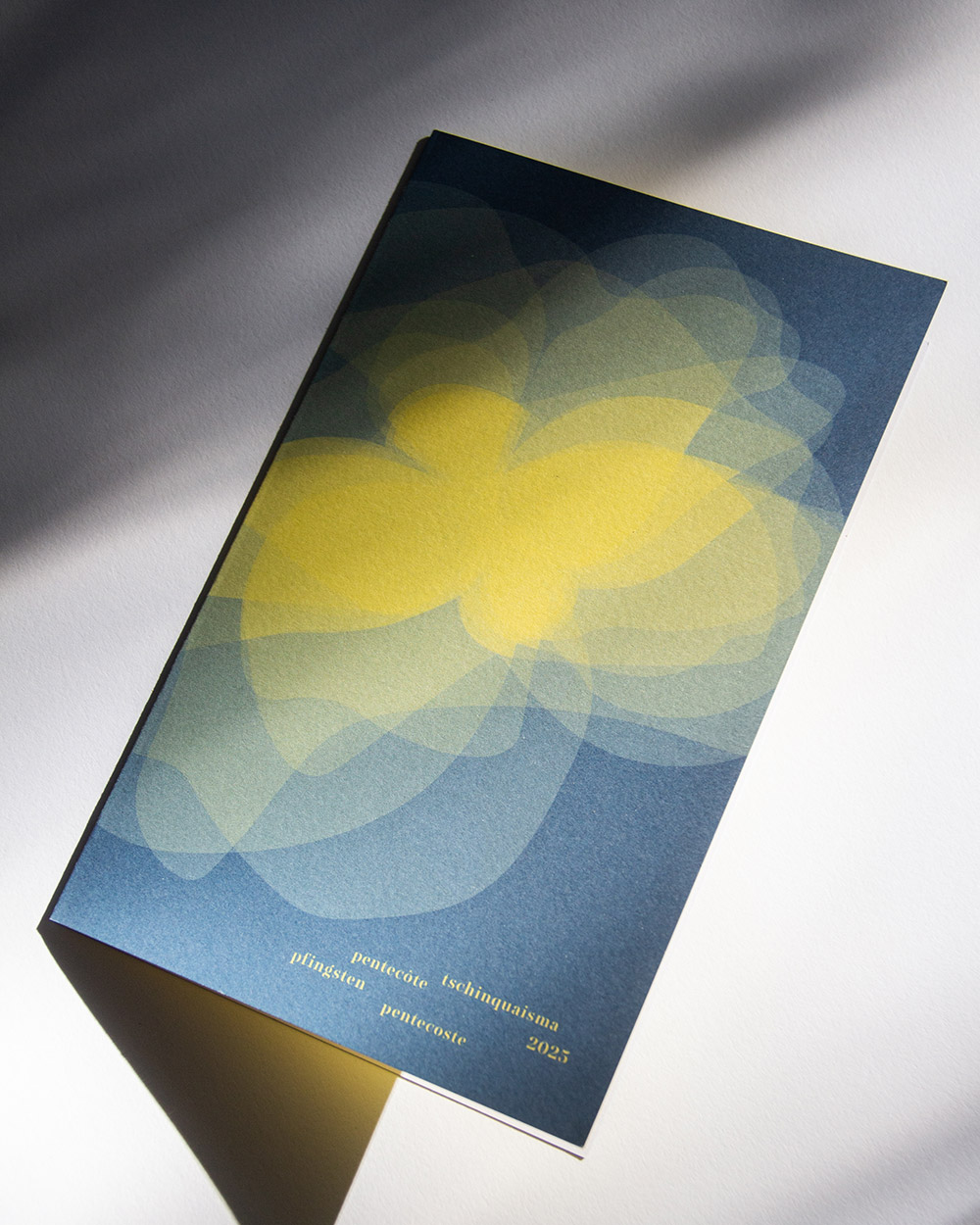 Karte mit abstraktem, gelbem Blumenmuster auf blauem Hintergrund und mehrsprachigem Pfingsttext 2025.
