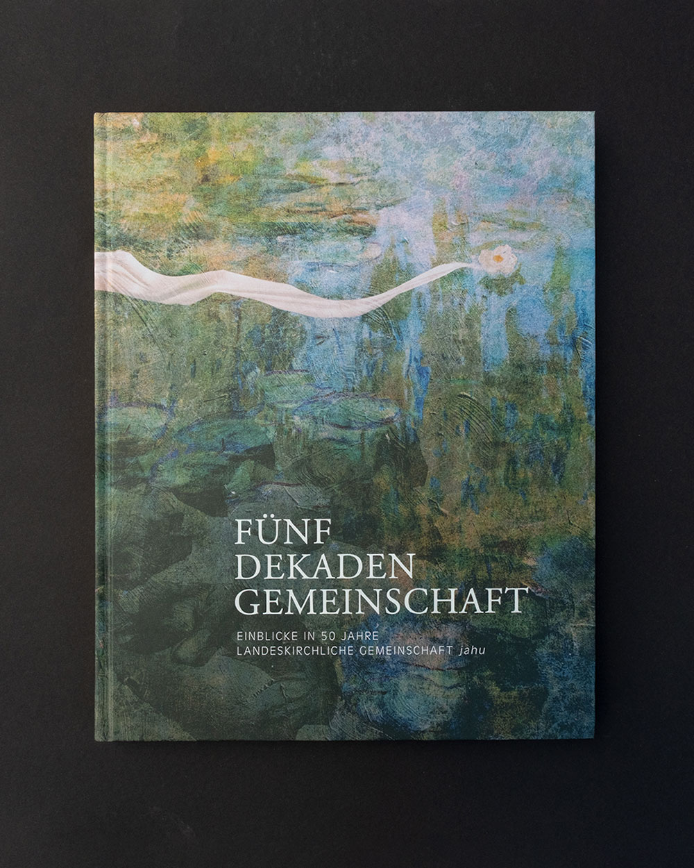 Buchcover mit impressionistischem Wasserlilienmotiv und dem Titel Fünf Dekaden Gemeinschaft.