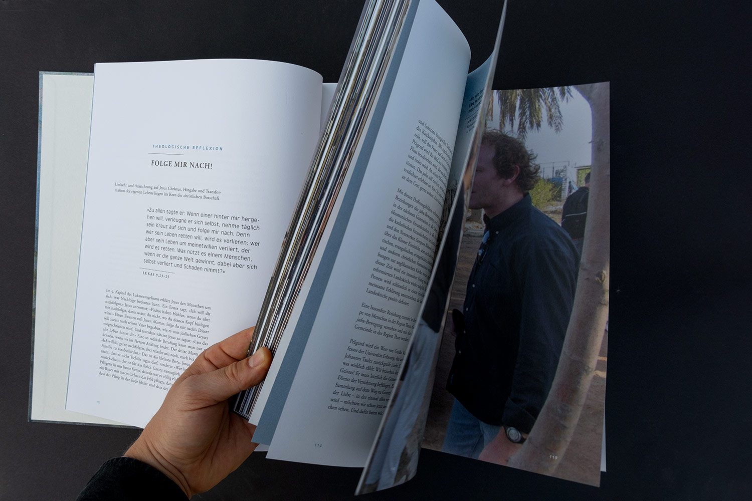 Hand blättert in einem Buch mit Text auf Deutsch und einem Bild eines Mannes im Freien.