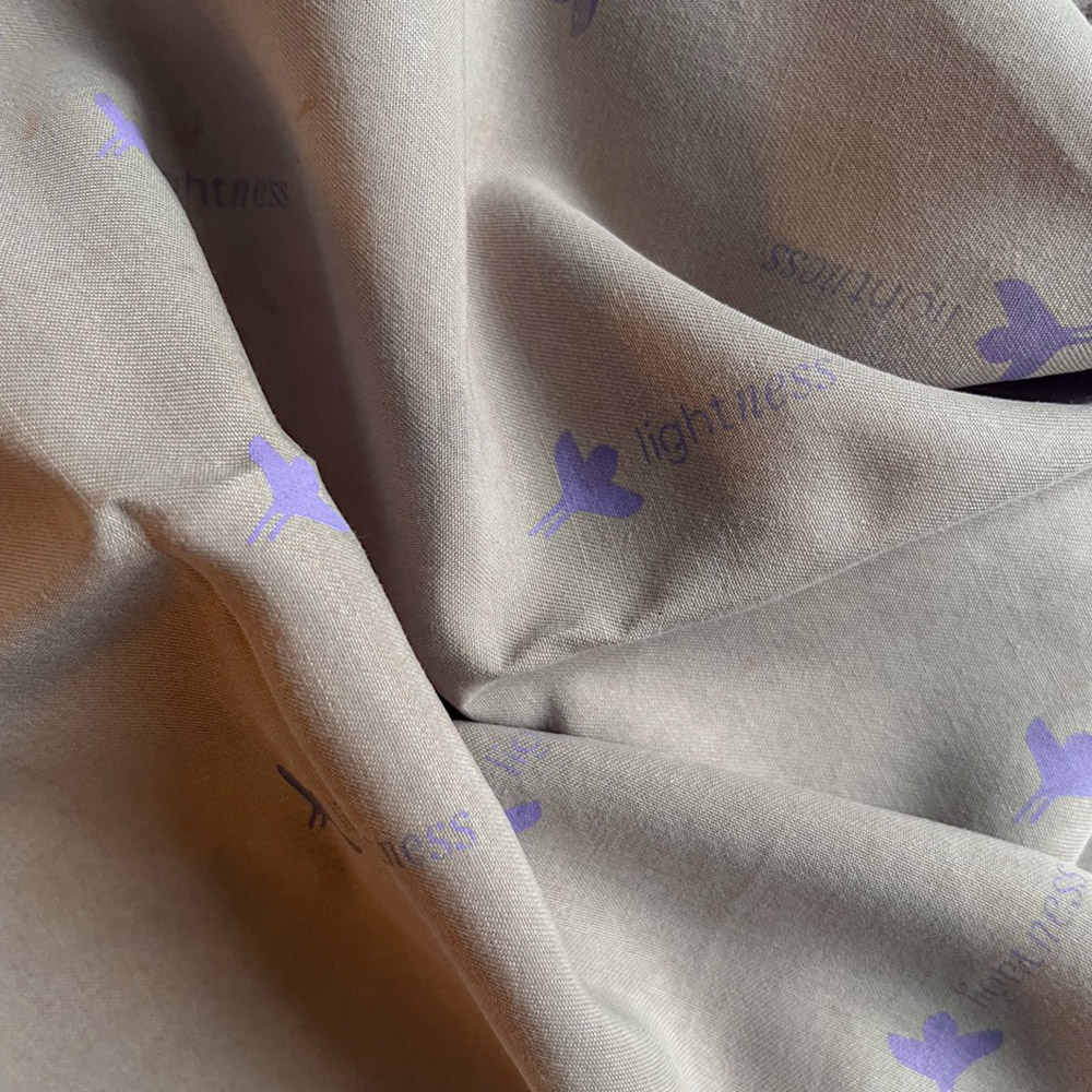Logo von Lightness als Siebdruckt in Lila auf grauem Stoff.