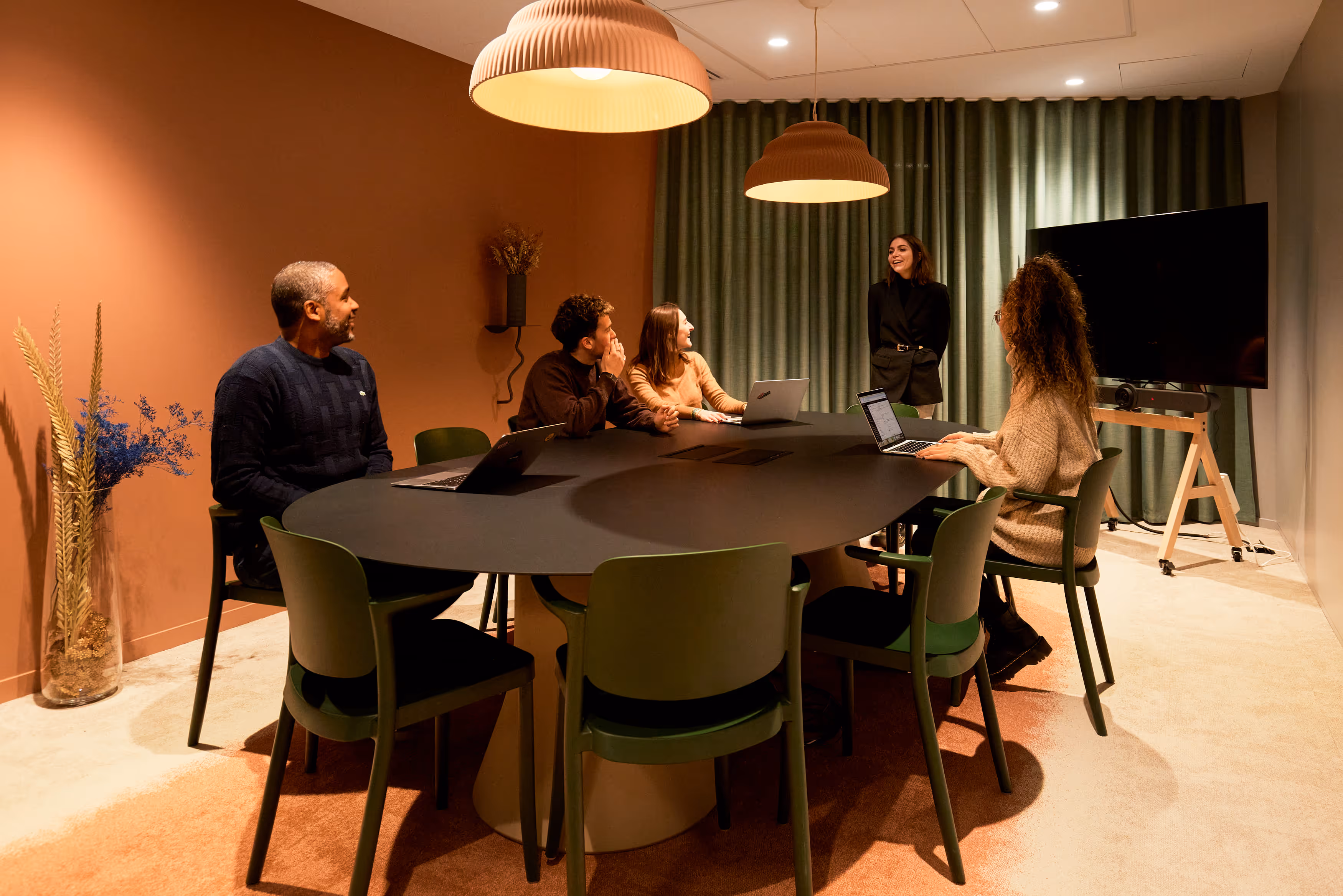 Une salle de réunion avec 5 personnes qui échange dans la bienveillance