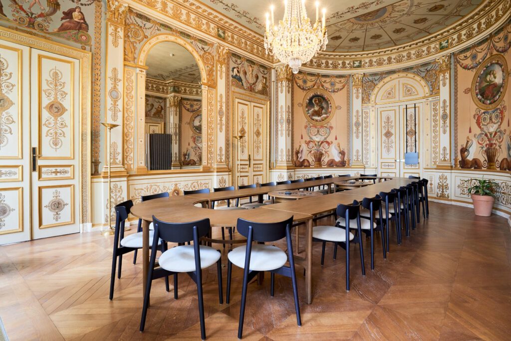 Salle avec de nombreux ornements avec un style Charles X, une table au centre et des chaises autour