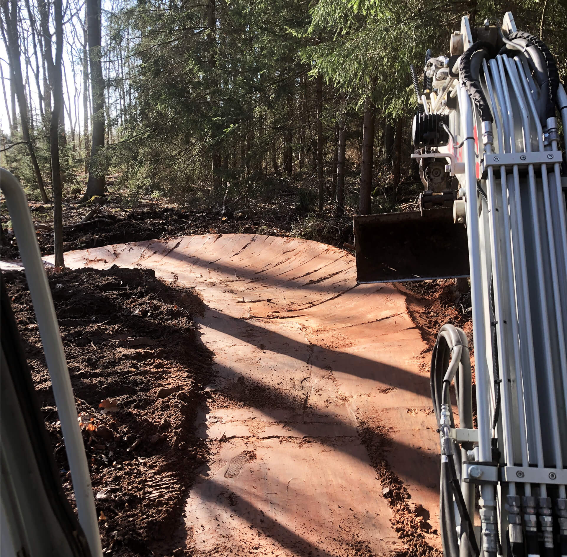 a mountainbiketrack in the forest and arm of an excuvater