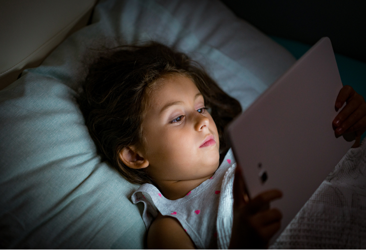 Young girl reading tablet in bed