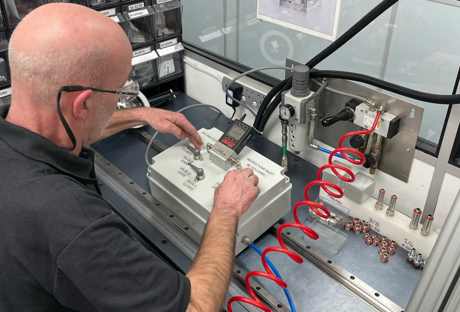 A Camozzi UK engineer conducting strict leak and functionality testing on a custom pneumatic control panel at a dedicated test bench inside the Automation Centre.