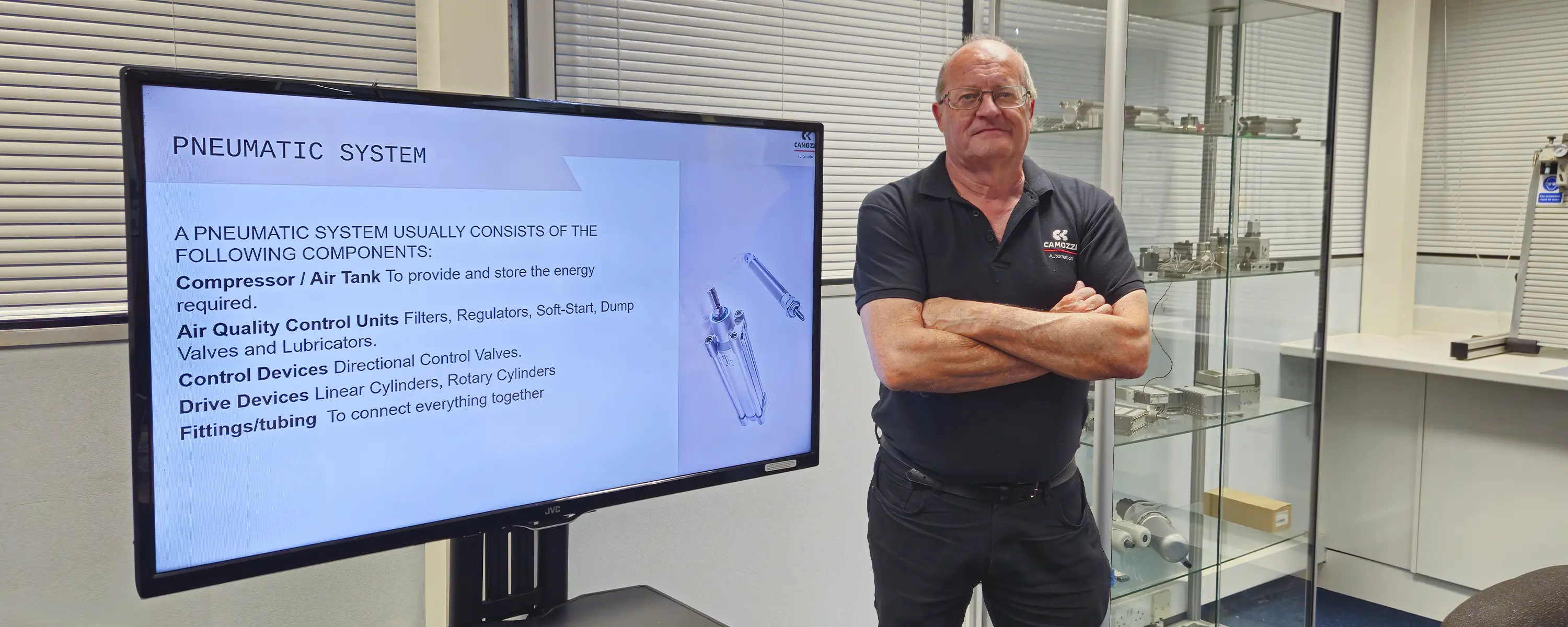 Steve Partington standing next to a presentation screen outlining the basic components of a pneumatic system during the Camozzi Automation UK Introduction to Pneumatics training course.
