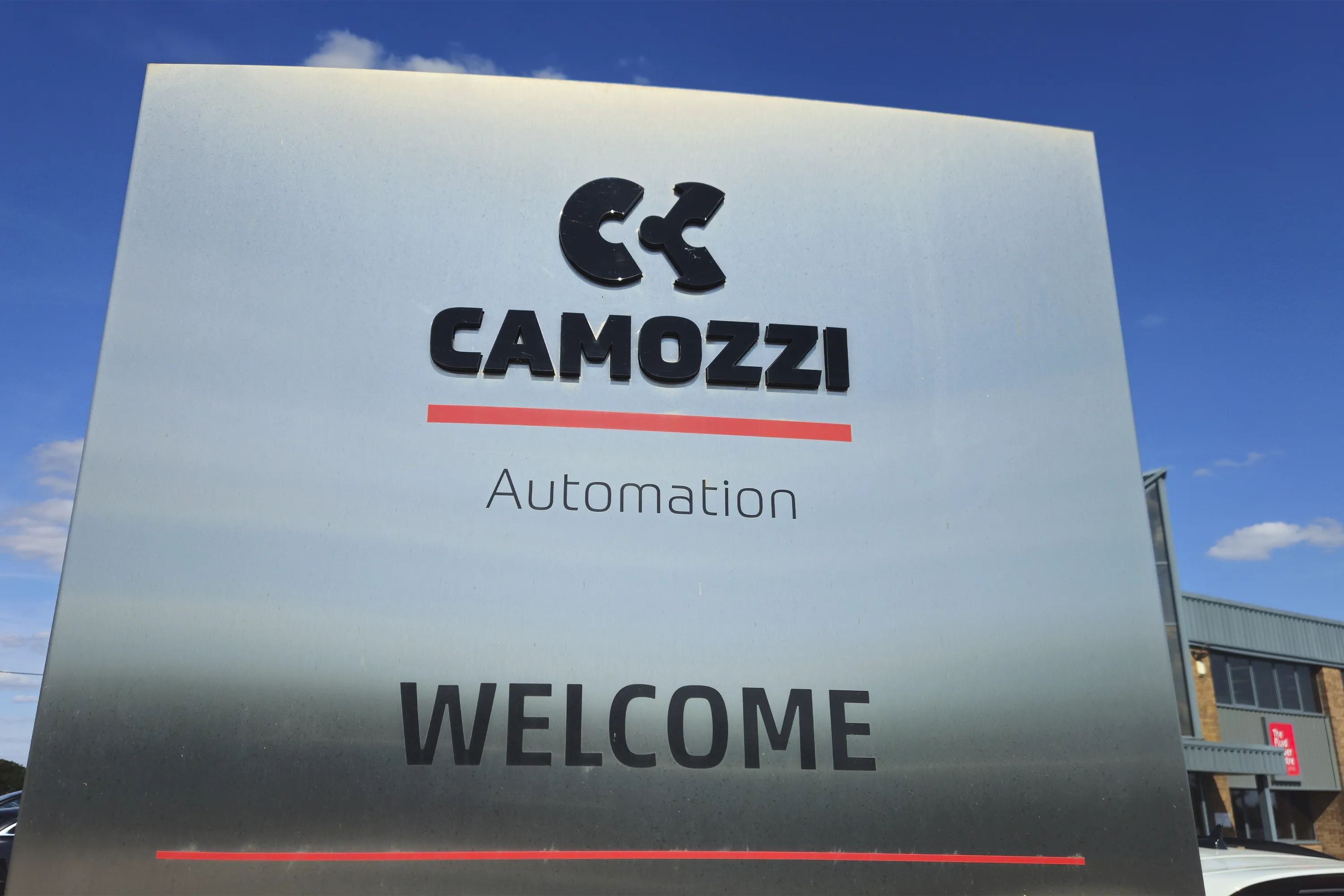 Large metal welcome sign displaying the Camozzi Automation logo outside the UK headquarters at the Fluid Power Centre, helping delegates locate the training facility.