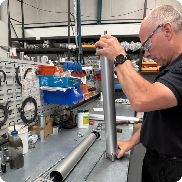 An engineer at the Camozzi UK workshop preparing and burnishing a precision piston rod before integrating it into the custom pneumatic cylinder barrel.