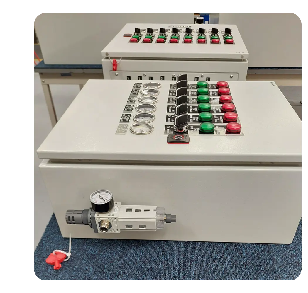 Exterior view of a sealed grey control panel featuring labeled operator controls including green and red push buttons, selector switches, dials, and an externally mounted air filter regulator.