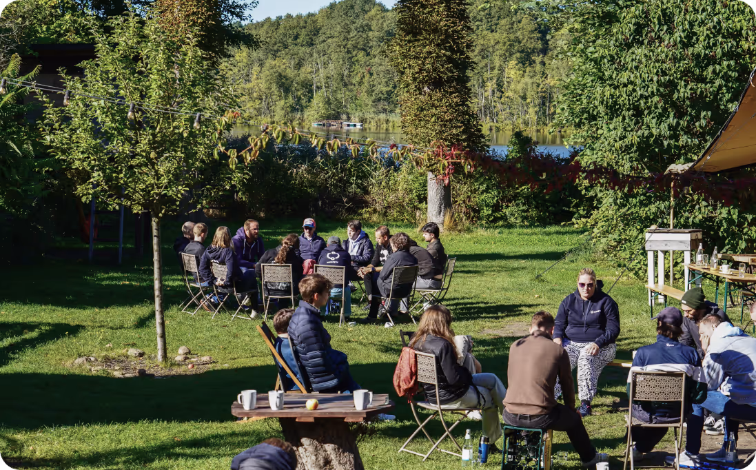 Arbeiten draußen beim Company Offsite 2025 - Mitarbeiter sitzen in entspannten Team-Runden in Stuhlkreisen