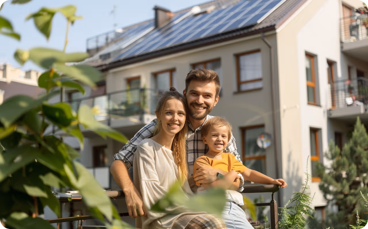 Glückliche Familie, Vater mit 2 Kindern vor Mehrfamilienhaus mit Solaranlage. Die Mieterstrommodelle Vollversorgung und Teilversorgung sind eine gute Option für Mieter und Vermieter bei Mieterstrom. / metergrid