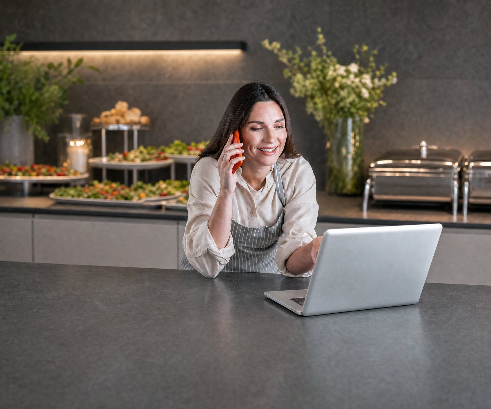 Catering-Disposition telefoniert mit dem Kunden und sieht am Laptop, wo der Transporter gerade ist