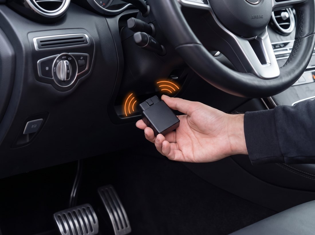 Hand steckt den TrackPro FMC003 in die OBD-Buchse eines Streifenfahrzeugs