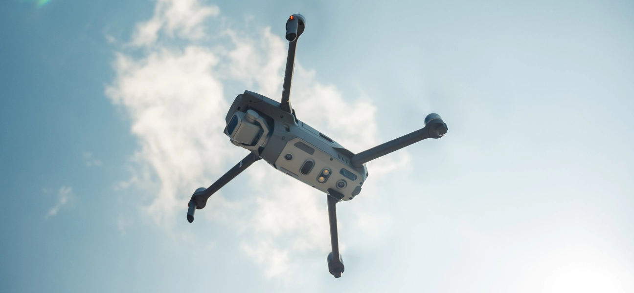 A drone flies against a sunny, blue sky