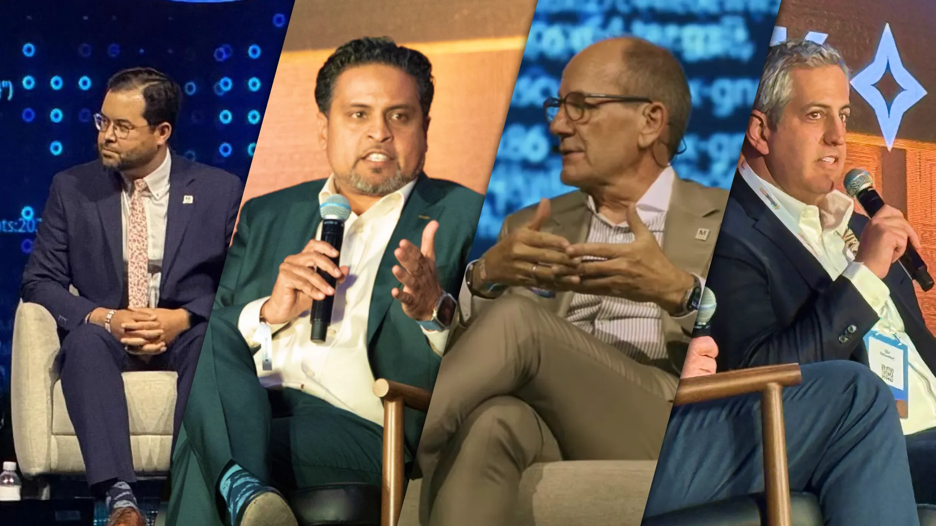 Four men in business attire speaking on stage at a panel discussion with microphones.