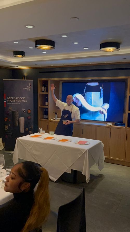 A Chef representing Seafood from Norway presenting to a room of guests.