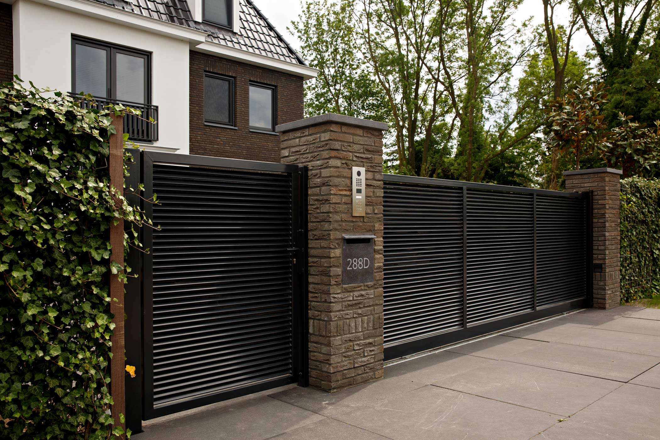 Moderne zwarte metalen toegangspoort met brievenbus en huisnummer 288D bij een woonhuis.