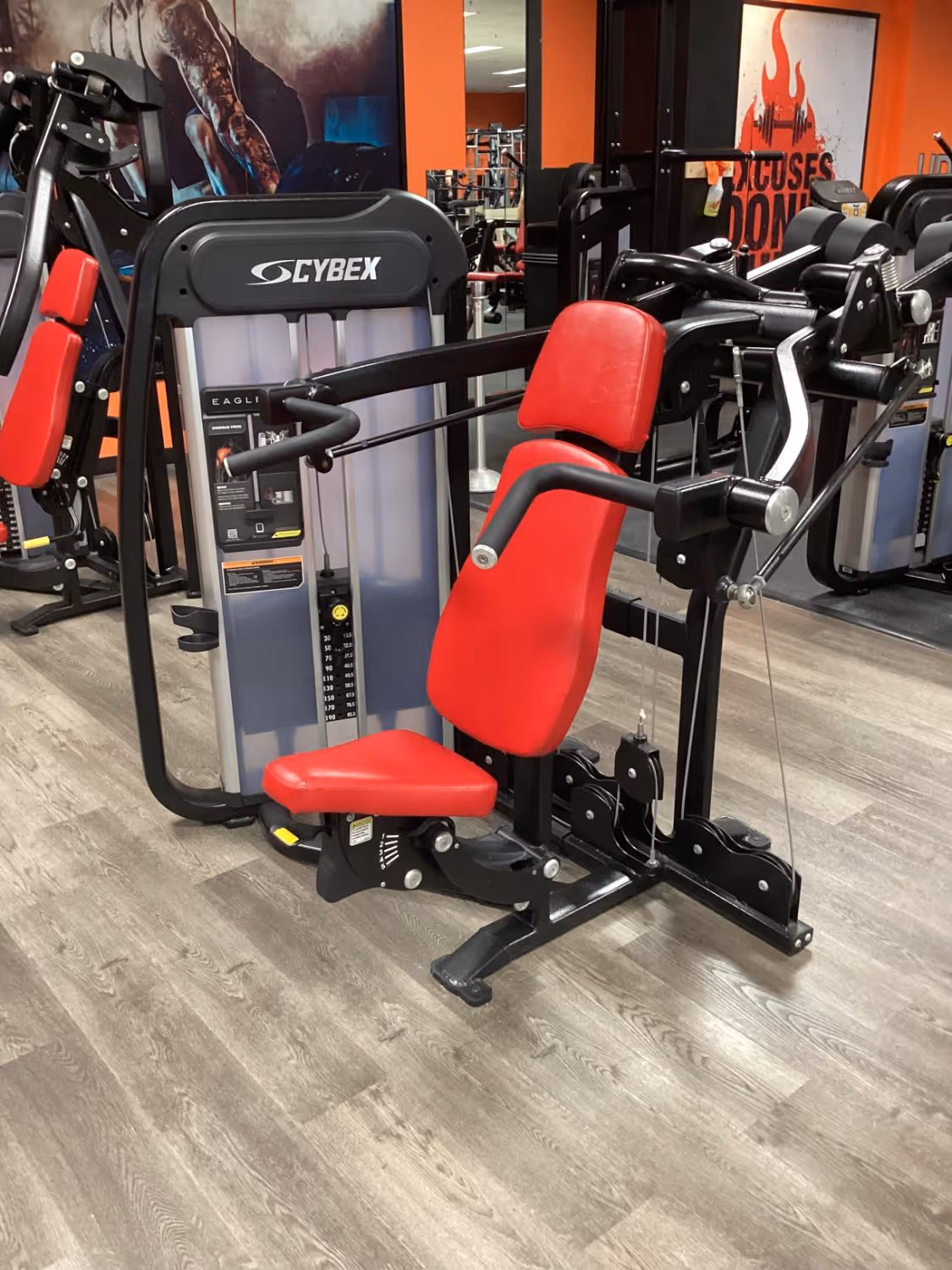 Cybex Eagle Pro gym machine with red padded seat and backrest designed for strength training.