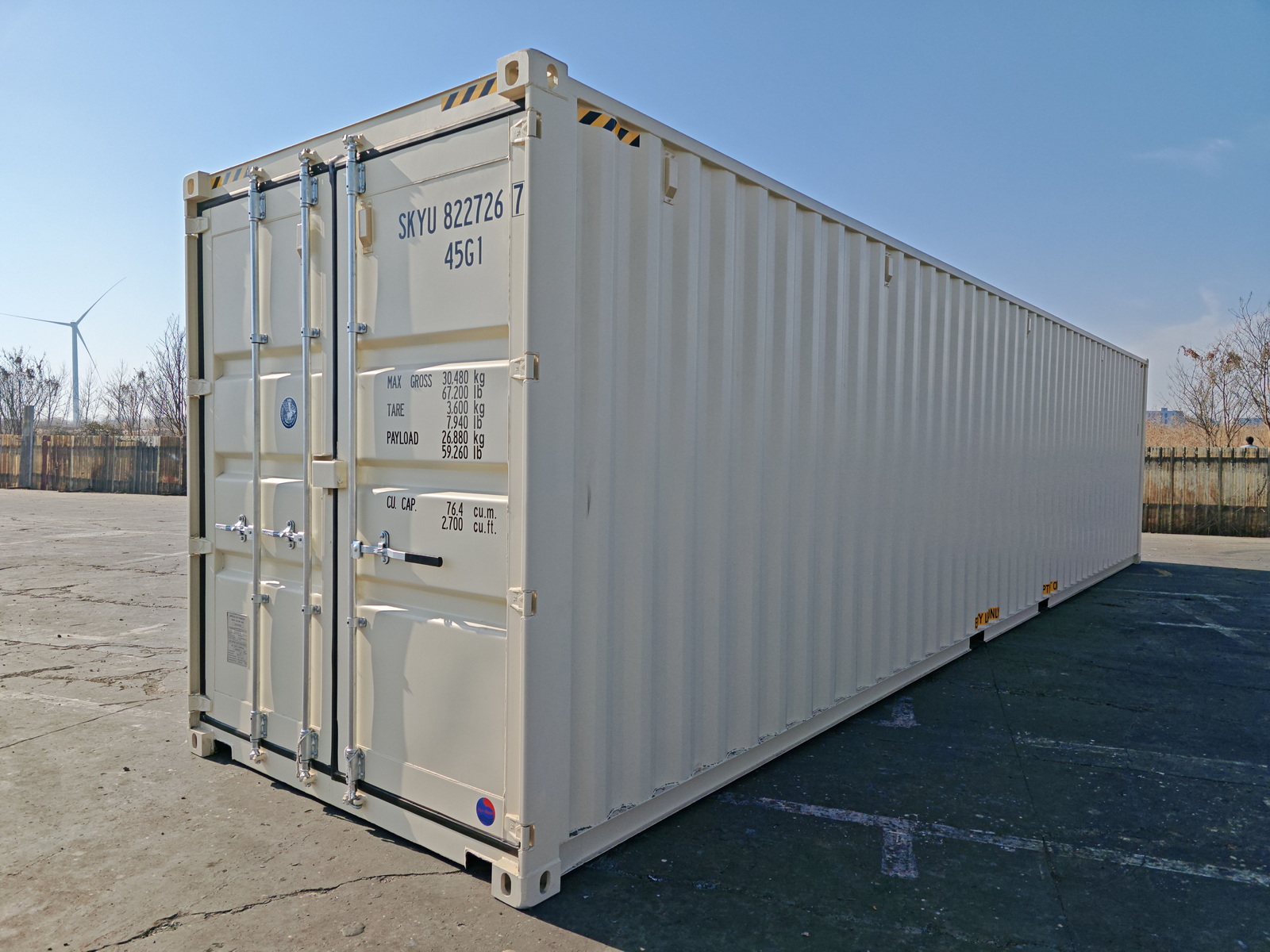 A creamy yellow shipping container in a large yard full of containers