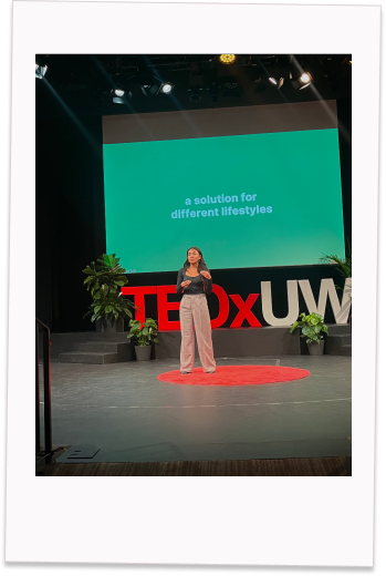 Julia giving her Tedx talk with a slide behind her labelled "a solution for different lifestyles"