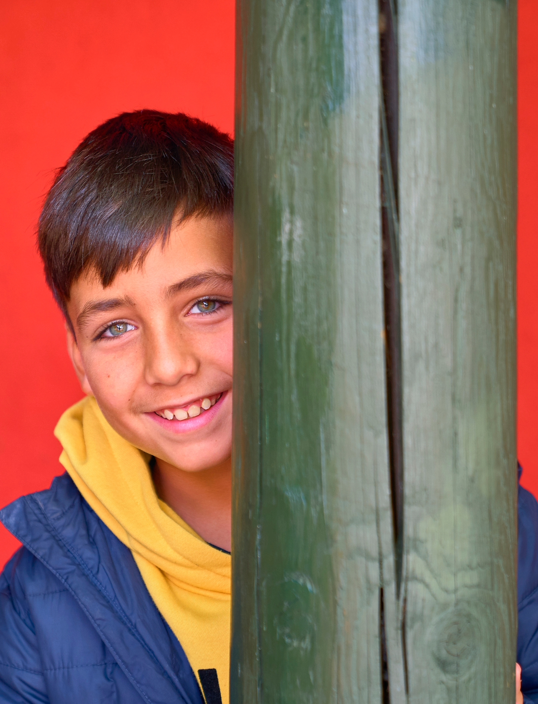 shy boy looking from behind a column