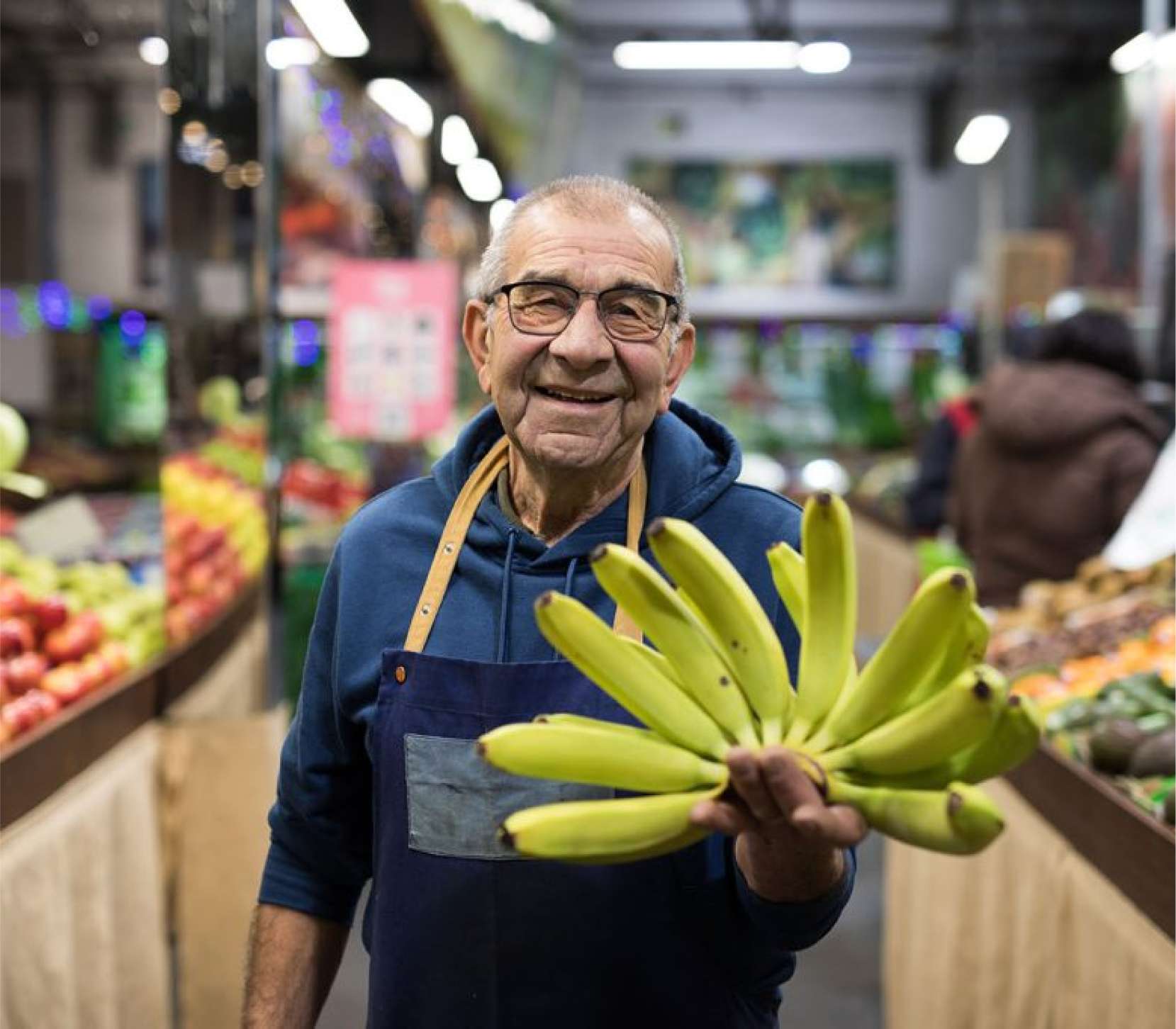 Fruit shop owner holding a bunch on bananas