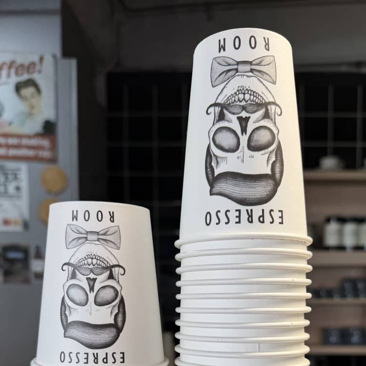 Stacks of coffee cups branded with the Espresso Room name and logo