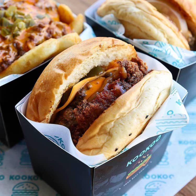 Delicious looking hamburgers nestled in finely printed cardboard packaging, lined with brand greaseproof paper