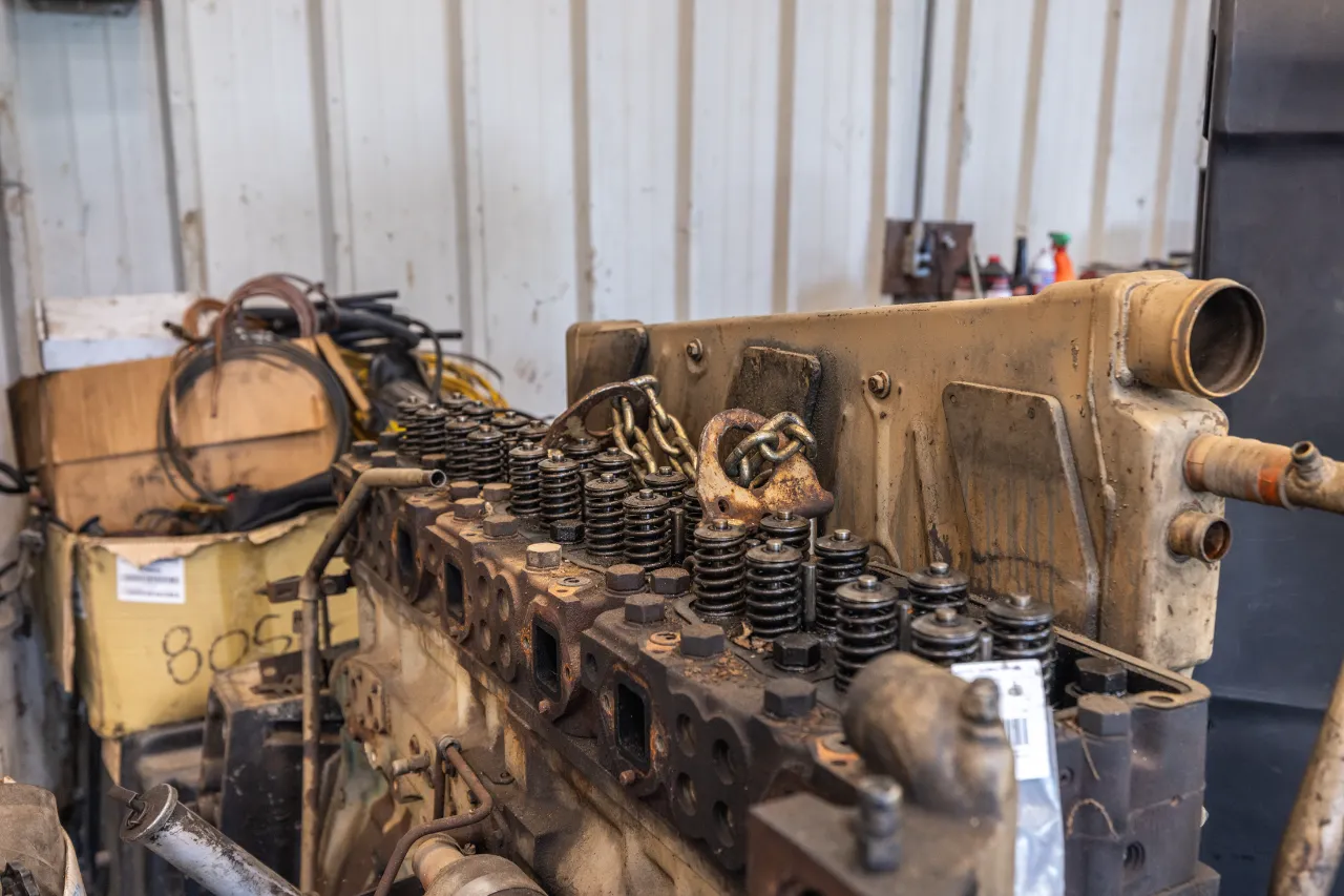 Disassembled diesel engine cylinder head with valve springs exposed, showing signs of wear and grime.
