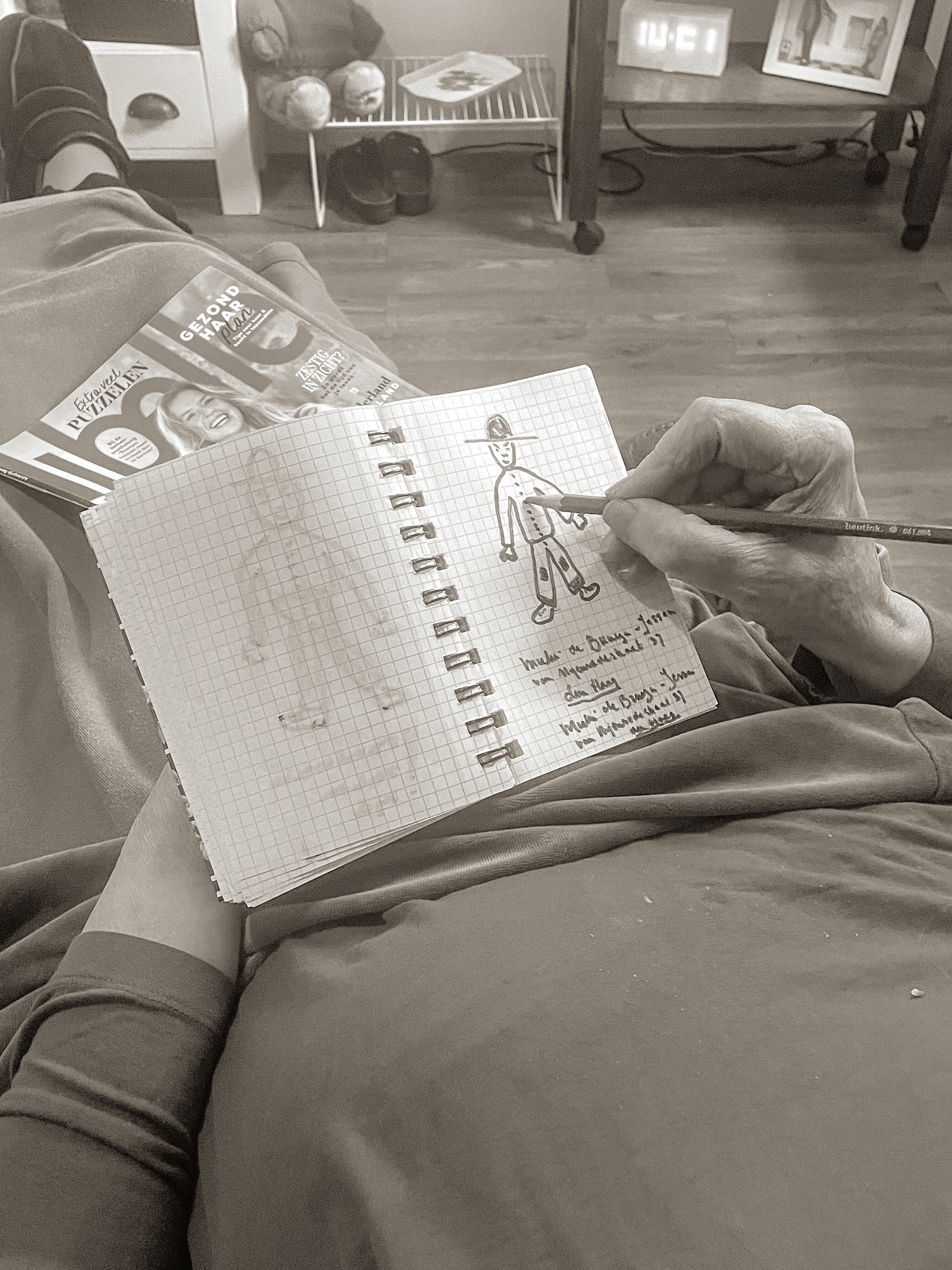 Een hand tekent een figuur in een schetsboek, creatieve activiteit op een psychogeriatrische afdeling