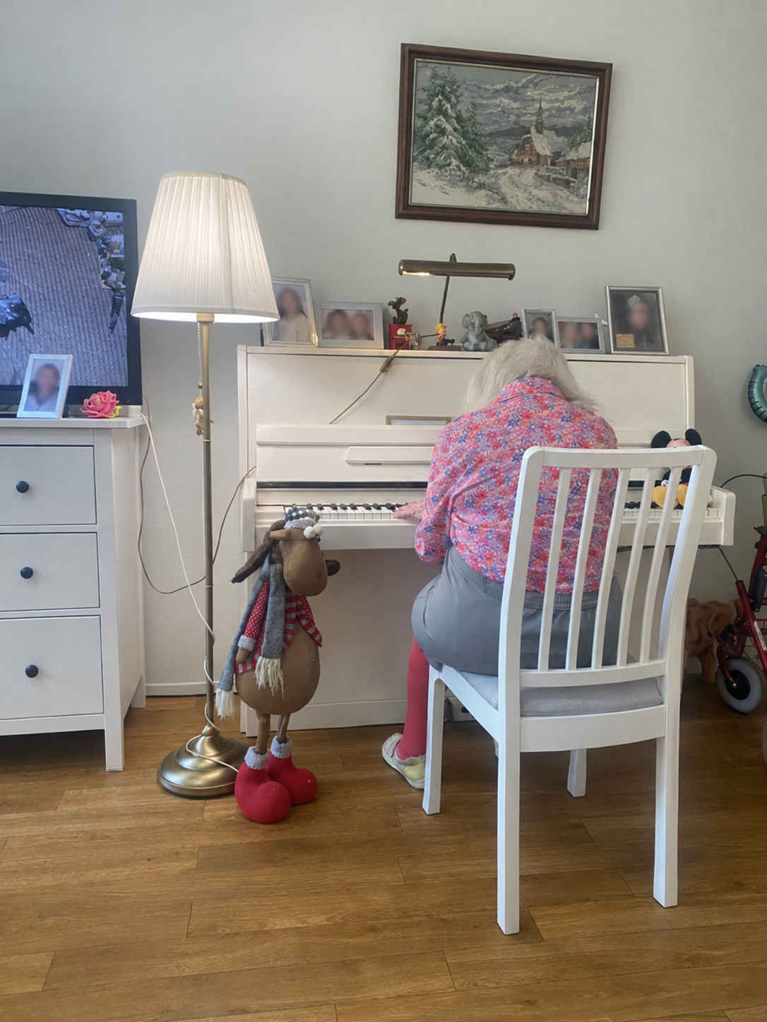 Een oudere vrouw speelt piano in haar eigen kamer, van achteren gefotografeerd