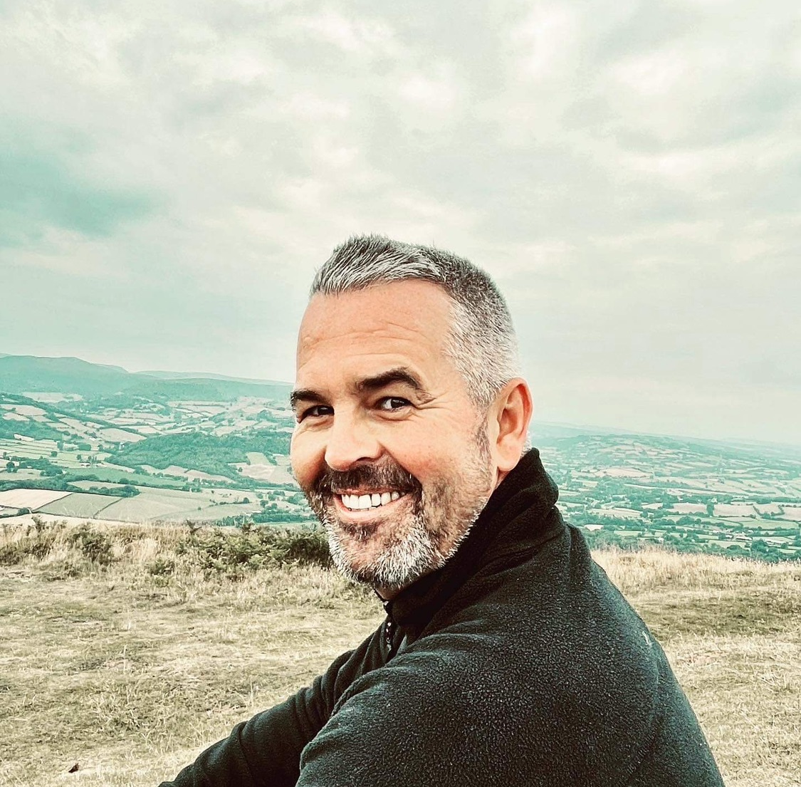 A head shot of Gareth Davies, project lead for See Cymru Differently with the Welsh hills in the background