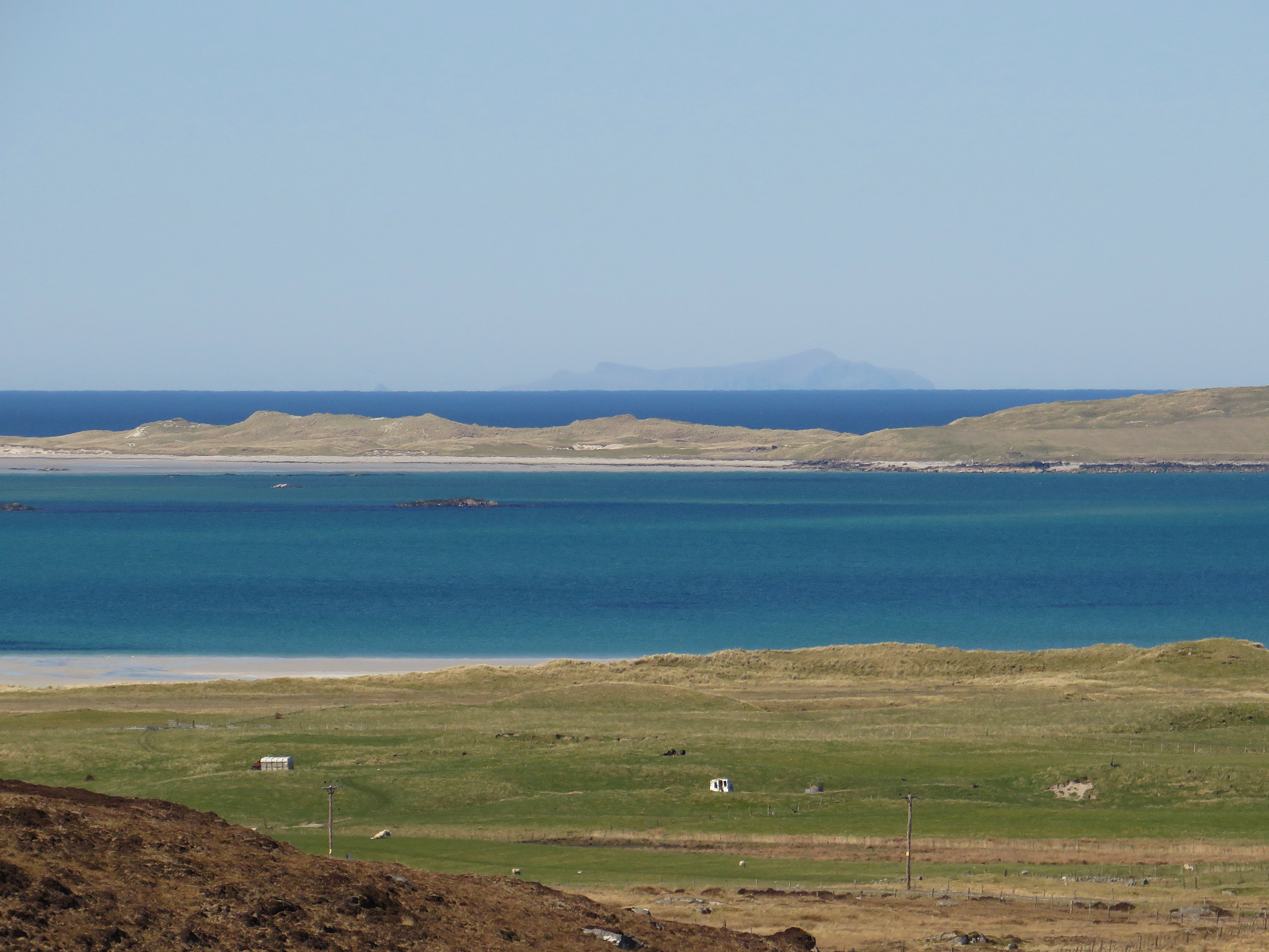 coastal plain and scattered houses, expanse of sea, outline of island in far distance